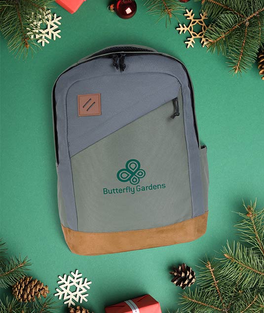 Logoed backpack on a green background with pinebows, ornaments, and gifts around it.
