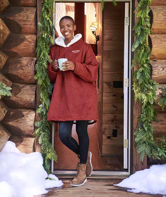Happy person in a custom wearable blanket on a snowy porch.