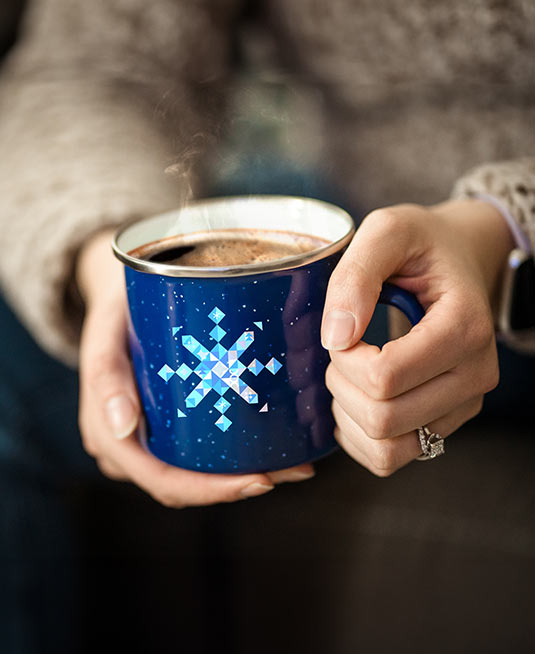 Person holding a mug with custom branding in their hands.