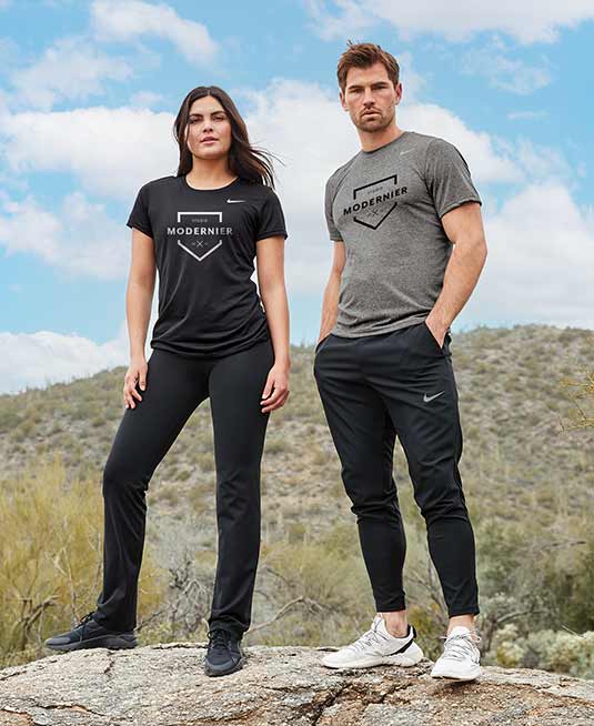 Two people wearing Nike t-shirts with custom logo, standing on a rock in the desert.