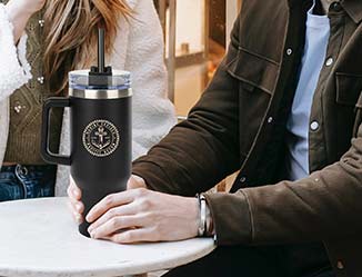 Person holding a stanley style, tumbler with straw printed with a custom logo.