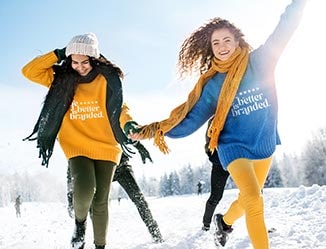 Happy people wearing sweatshirts with logos playing in the snow.