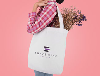 Cotton tote bag with logo over a persons shoulder carrying flowers