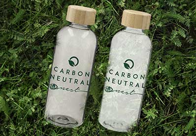 Glass water bottle with custom logo on a natural green background
