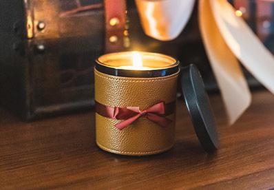 A lit candle with a gift bow, sitting on a table.