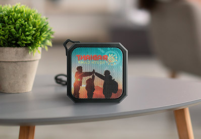 Speaker, with full color custom print on the front, sitting on an outdoor table.