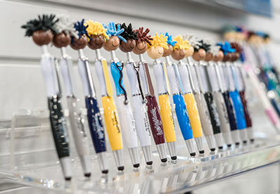 Multiple colors of MopTopper pens with logos lined up at a trade show.